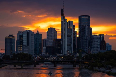 The sun breaks through the clouds behind the Frankfurt banking skyline shortly in front of setting,
