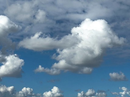 Cumulus clouds at the bottom edge of the image, large white cumulonimbus cluster cloud towering in