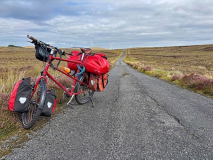 A fully loaded bicycle stands on a long country road in a wide landscape, Adventure, Cycling tour,