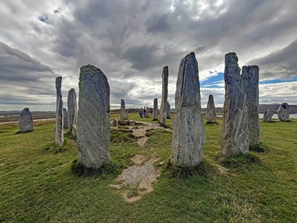 A mystical stone circle under a cloudy sky surrounded by green landscape, Callanish, Isle of Lewis