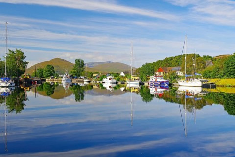 Calm river landscape with anchored boats and clear reflections, Caledonian Canal, Fort William,