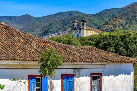 Old weathered colonial house with a baroque church and mountain in the background in the historic