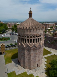 Distinctive stone tower in an urban setting under a blue sky, aerial view, Holy Archangel Church,