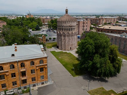 A round tower in an urban setting with surrounding trees and historic buildings, aerial view, Holy