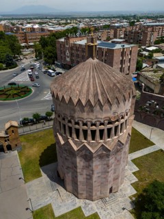 A tower with reddish stones, surrounded by streets and buildings, bird's eye view, aerial view,