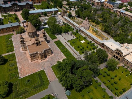 Bird's eye view of historic church surrounded by manicured gardens in an urban setting, aerial