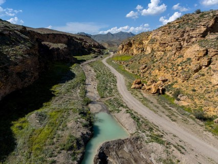 A path leads through a rocky valley with a narrow river flowing through the landscape, aerial view,