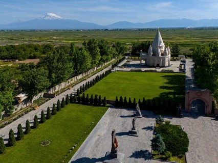 A picturesque landscape with a temple and mountains in the background under a blue sky, aerial