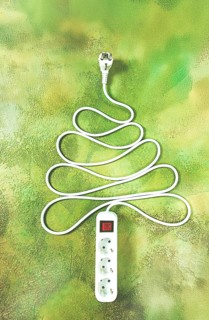 A power strip is arranged in the shape of a Christmas tree, artistically placed on a vibrant green