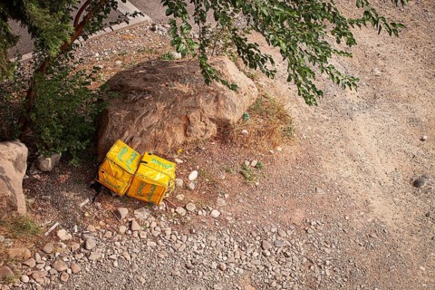 08/25/2025 Georgia, Tbilisi, Delivery packages, Glovo company, left on stony ground, near bushes,