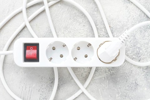 Power strip with multiple sockets and a switch in a cluttered setup on a textured surface during