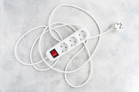 Power strip with multiple sockets and a switch in a cluttered setup on a textured surface during