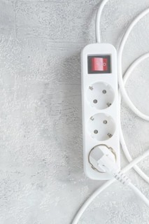 Power strip with multiple sockets and a switch in a cluttered setup on a textured surface during
