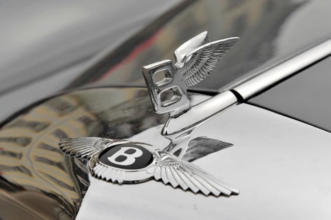 Bentley emblem on a shiny bonnet, symbolising luxury and elegance, Retro Classics meets Baroque,