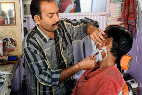 Kota, Rajasthan, North India, Asia, A barber shaves a customer's face in a small hairdressing