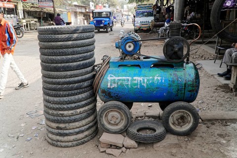 Kota, Rajasthan, North India, Asia, A pile of tyres next to a blue compressor in a dusty workshop