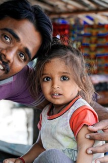 Kota, Rajasthan, North India, Asia, man with little girl, both smiling, in front of a colourful