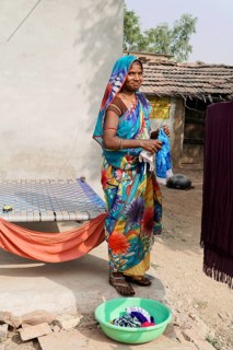 Kota, Rajasthan, North India, Asia, A woman in a colourful garment washes clothes in a rural