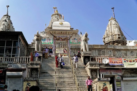 Entrance to Jagdish Temple, Udaipur, People climb the steps to a temple flanked by statues under a