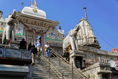 Entrance to Jagdish Temple, Udaipur, people climb the steps to a temple flanked by statues under a