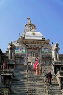 Entrance to Jagdish Temple, Udaipur, People climb the steps to a temple flanked by statues under a
