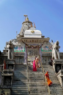 Entrance to Jagdish Temple, Udaipur, people climb the steps to a temple flanked by statues under a