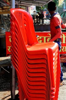 Udaipur, Rajasthan, North India, India, Asia, Stacked red plastic chairs in a lively market with