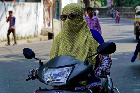Udaipur, Rajasthan, North India, India, Asia, A veiled woman with sunglasses rides a motorbike on a