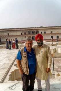 Red Fort, Agra, Uttar Pradesh, India, Two men smile warmly against a historic backdrop while groups