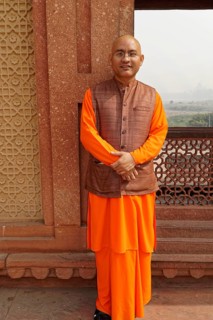 Agra, Uttar Pradesh, India, Asia, A monk in orange-coloured clothes stands in front of a historical