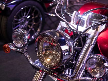 Retro motorbike with shiny chrome headlights and reddish finish, light reflections visible,