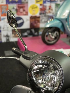 Retro scooter mirror in front of a blurred background with posters and another scooter, dortmund,