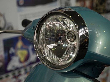 Close-up view of a retro scooter headlight with shiny chrome and a blue housing, dortmund,