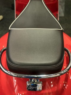 Black motorbike seat with white stitching on red base and chrome handle, dortmund, deutchland