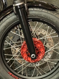 Close-up of a motorbike tyre with red brake caliper and spokes on dark ground, dortmund, germany