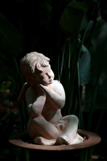 Stone sculpture of a pensive angel in a dark, shady garden, südlohn, westphalia, germany
