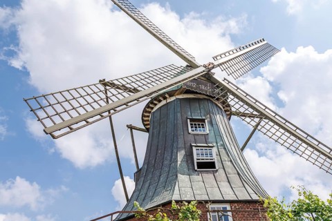 Historic windmill with wooden sails in front of a blue sky and clouds, südlohn, westphalia, germany