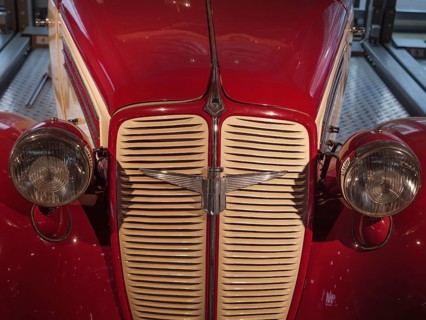Front view of a red classic car, emphasising the radiator grille and round headlights, Cologne,