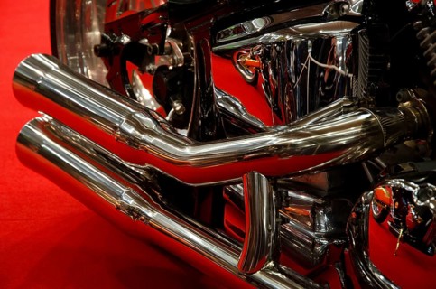 Close-up of a shiny exhaust system in chrome with red background, dortmund, germany