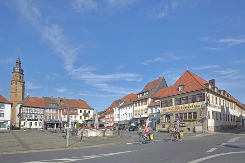 Market square with historic Schlundhaus, cyclist, steeple of the Church of the Assumption of the