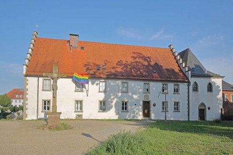 Hospital building built in the 16th century with crucifix and rainbow flag, peace flag, Lower