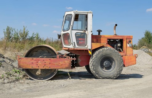 A roller-compactor in sunny illuminated building lot ambiance
