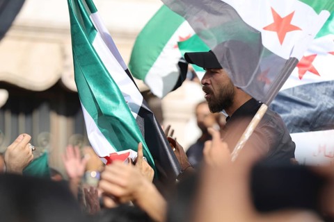 Thousands of Syrians march in Idlib carrying the Syrian revolutionary flag during a protest against