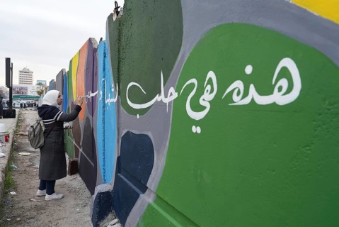 Young volunteers paint murals on walls to decorate the city following the fall of Bashar al-Assad's