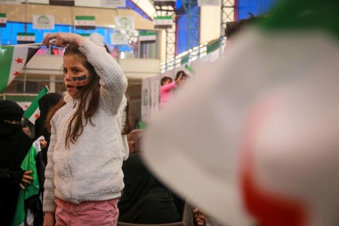 Syrians are seen demonstrating against the rule of Bashar al-Assad while carrying banners and the