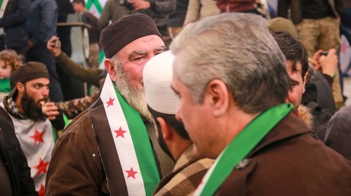 Syrians are seen demonstrating against the rule of Bashar al-Assad while carrying banners and the