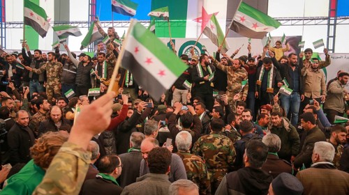 Syrians are seen demonstrating against the rule of Bashar al-Assad while carrying banners and the