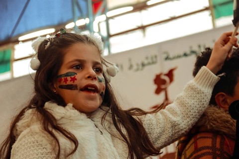 Syrians are seen demonstrating against the rule of Bashar al-Assad while carrying banners and the