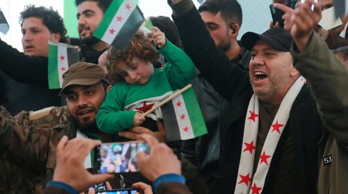 Syrians are seen demonstrating against the rule of Bashar al-Assad while carrying banners and the