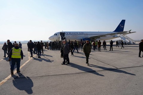 Passengers celebrate with Syrian revolutionary flags as the first flight lands at Aleppo